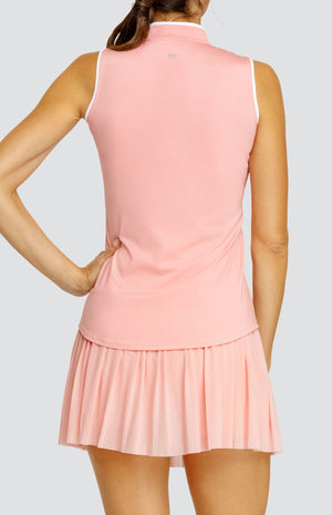 Model wearing a light pink sleeveless top with an open v neck collar with white accents and side vents. Paired with a matching mesh pleated skort with solid undershorts.